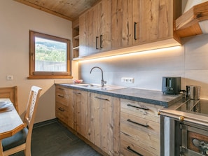 Una cocina con armarios de madera, un fregadero y un ventanal con vistas al paisaje.