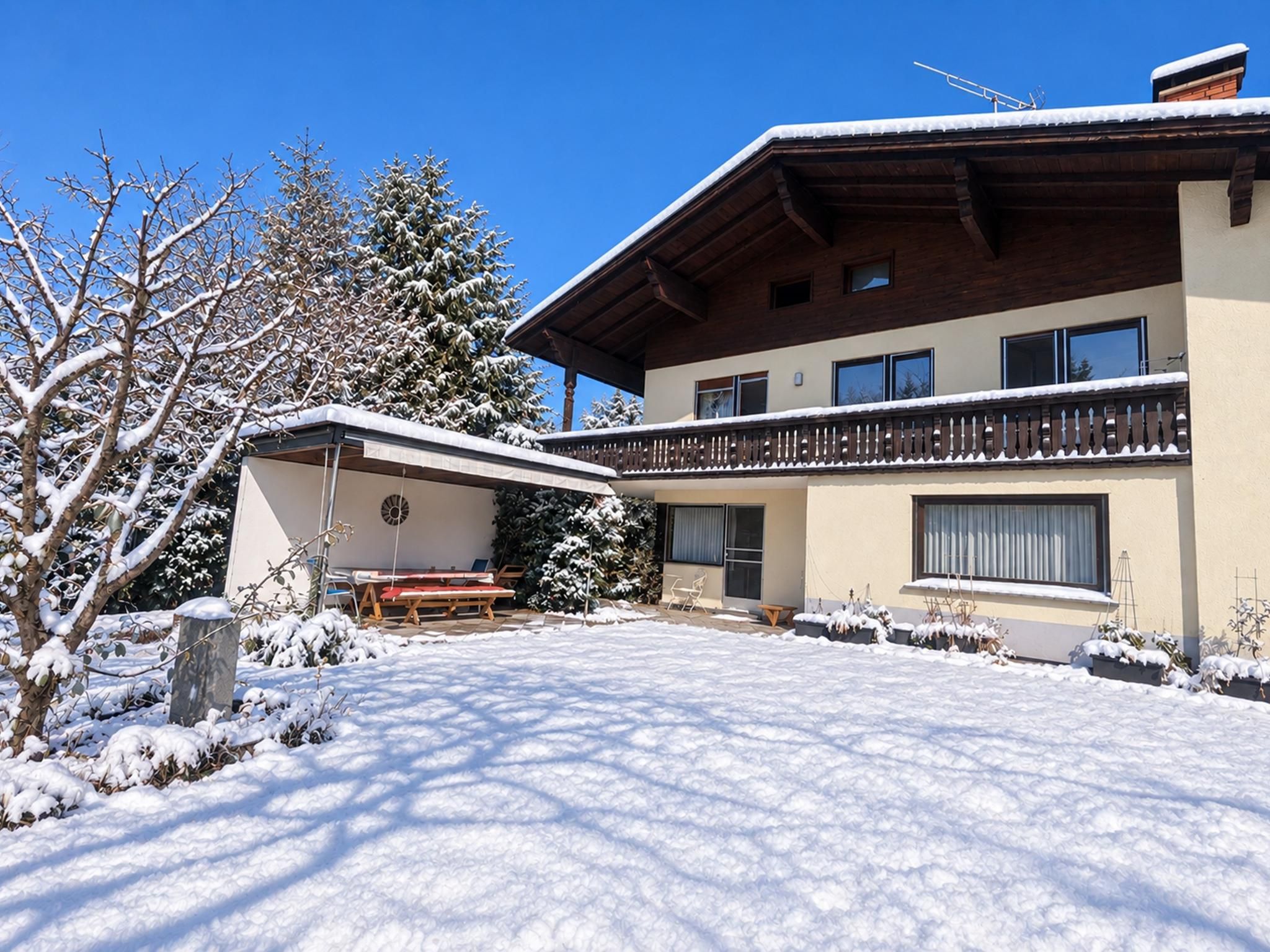 A two-story building with a balcony, a covered outdoor seating area, and snow-covered surroundings.