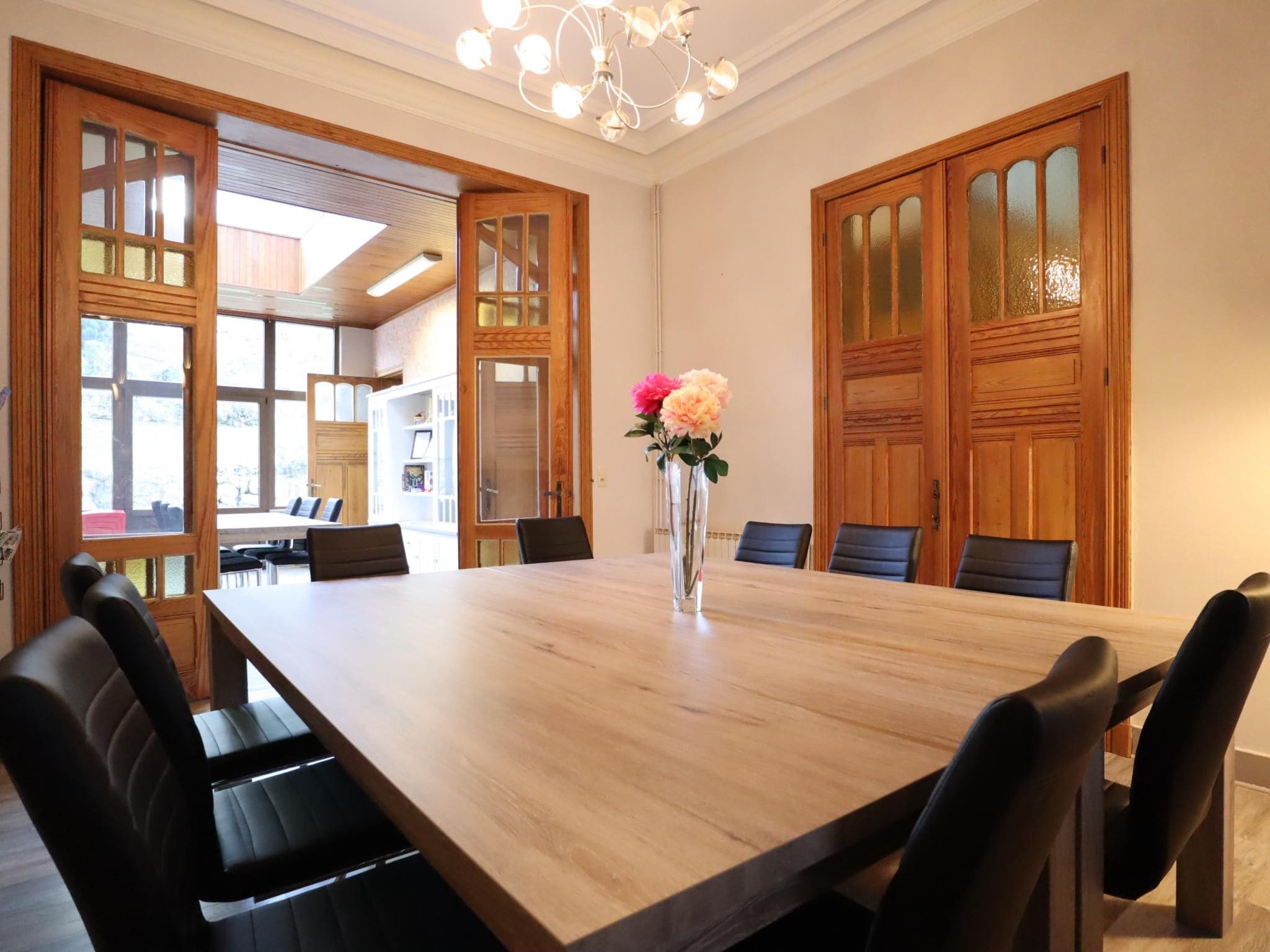 A conference room with a long table, chairs, and a vase with flowers.