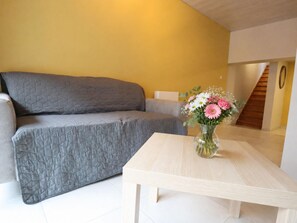 A living room with a grey sofa, a wooden coffee table, and a vase of flowers. - Nice little cottage in the heart of Dinant! (Dinant)