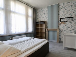 A bedroom with a bed, a wardrobe, a radiator, and a wall-mounted shelf. - Group house in a typical style in Dinant (Dinant)