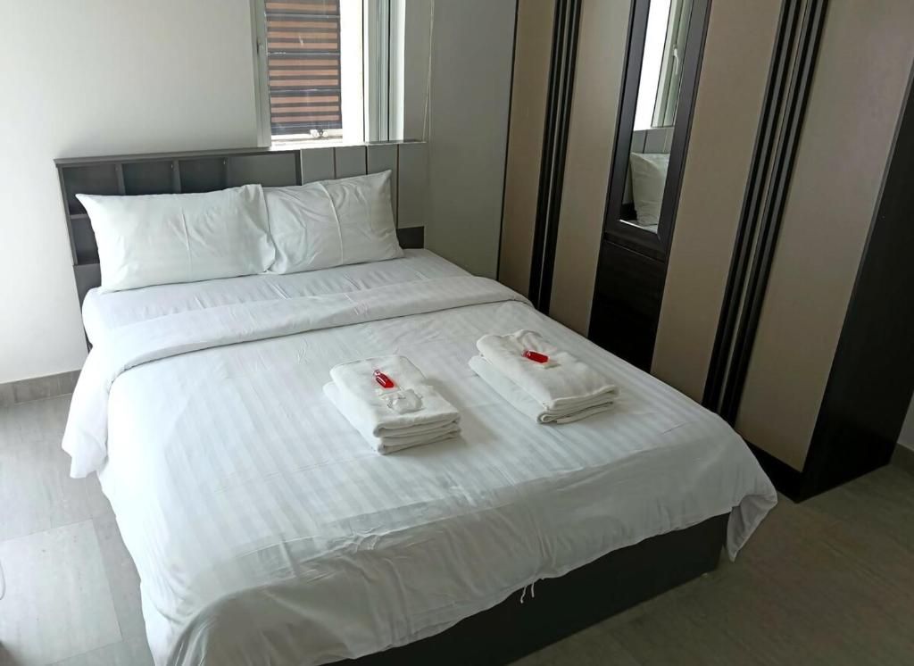 A hotel room with a bed, two towels, a window, and a mirror.
