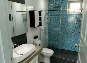 Et badeværelse med hvid vask, toilet og bruseniche.