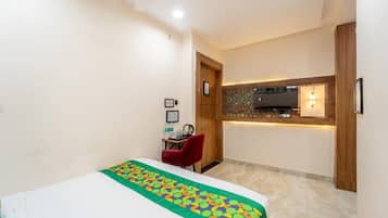 A hotel room with a bed, a desk, and a kitchenette area.