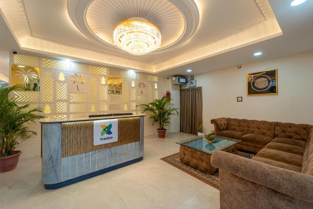 Un área de recepción con mostrador, candelabro, sofá y un diseño de pared con motivos.