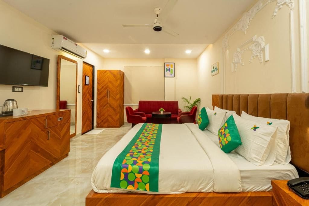 Una habitación de hotel con cama, escritorio, televisor, armario y sofá rojo.
