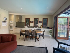 A modern kitchen with a dining area, built-in appliances, and large windows. - House with own private pool, an easy walk to the Beach, Restaurants and Cafe's (Cronulla)