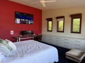 A bedroom with a bed, a desk with a flat-screen TV, a window with blinds, and a ceiling fan. - House with own private pool, an easy walk to the Beach, Restaurants and Cafe's (Cronulla)