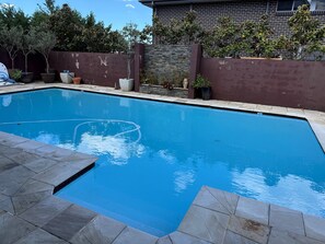 A rectangular swimming pool with a stone border, surrounded by a brick wall and potted plants. - House with own private pool, an easy walk to the Beach, Restaurants and Cafe's (Cronulla)