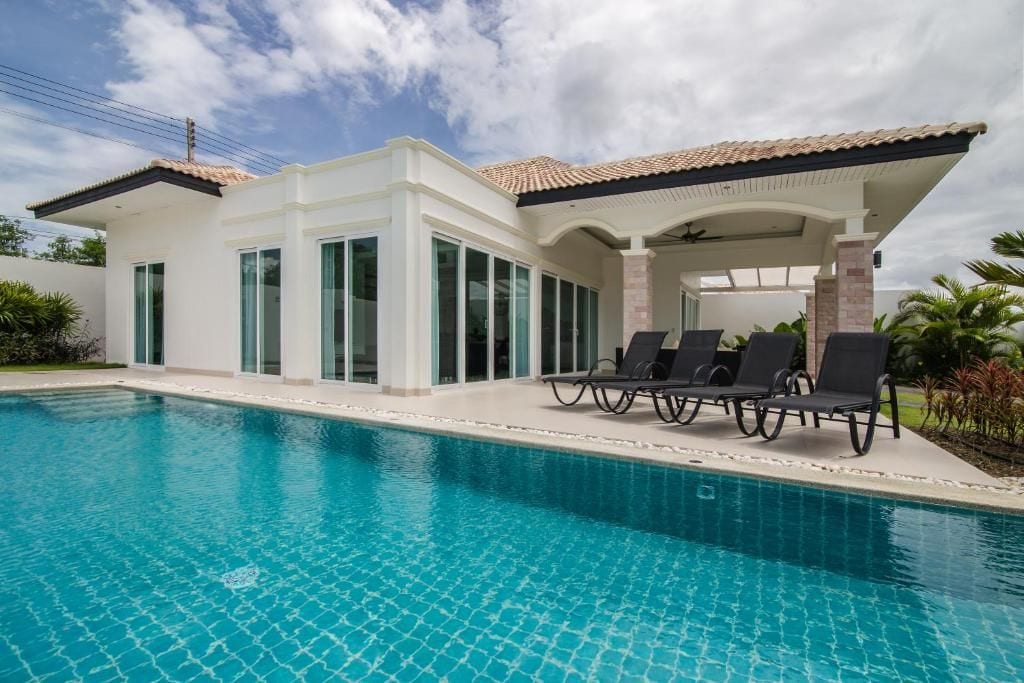 A modern house with a swimming pool, large windows, and a covered patio area.