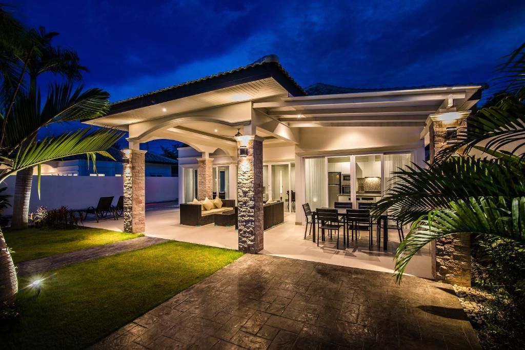A modern house with a covered patio, outdoor seating, and a stone exterior.