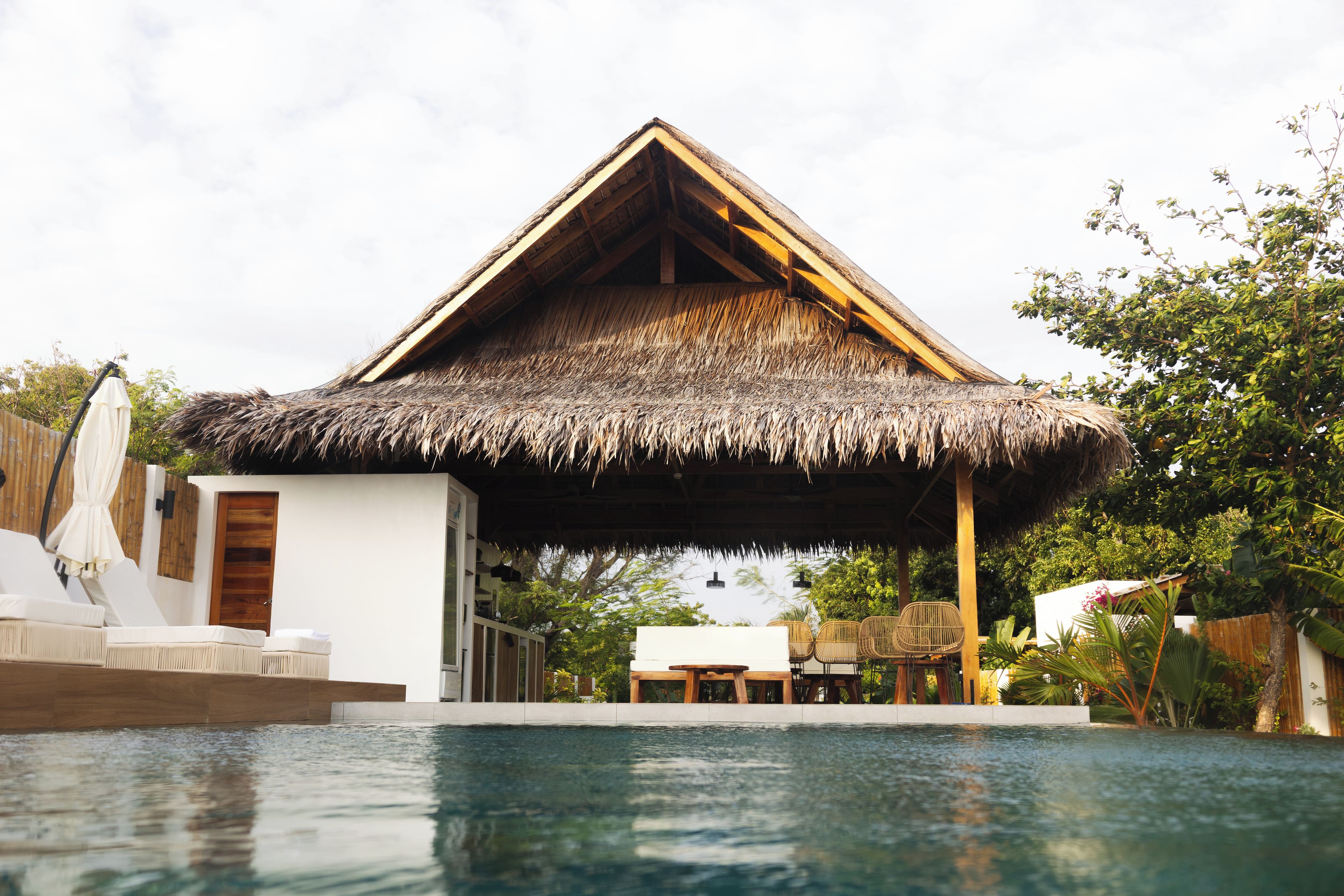 A thatched-roof structure with a pool in front.
