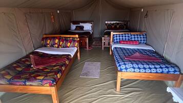 A tent with two beds, a table, and a hanging light fixture.