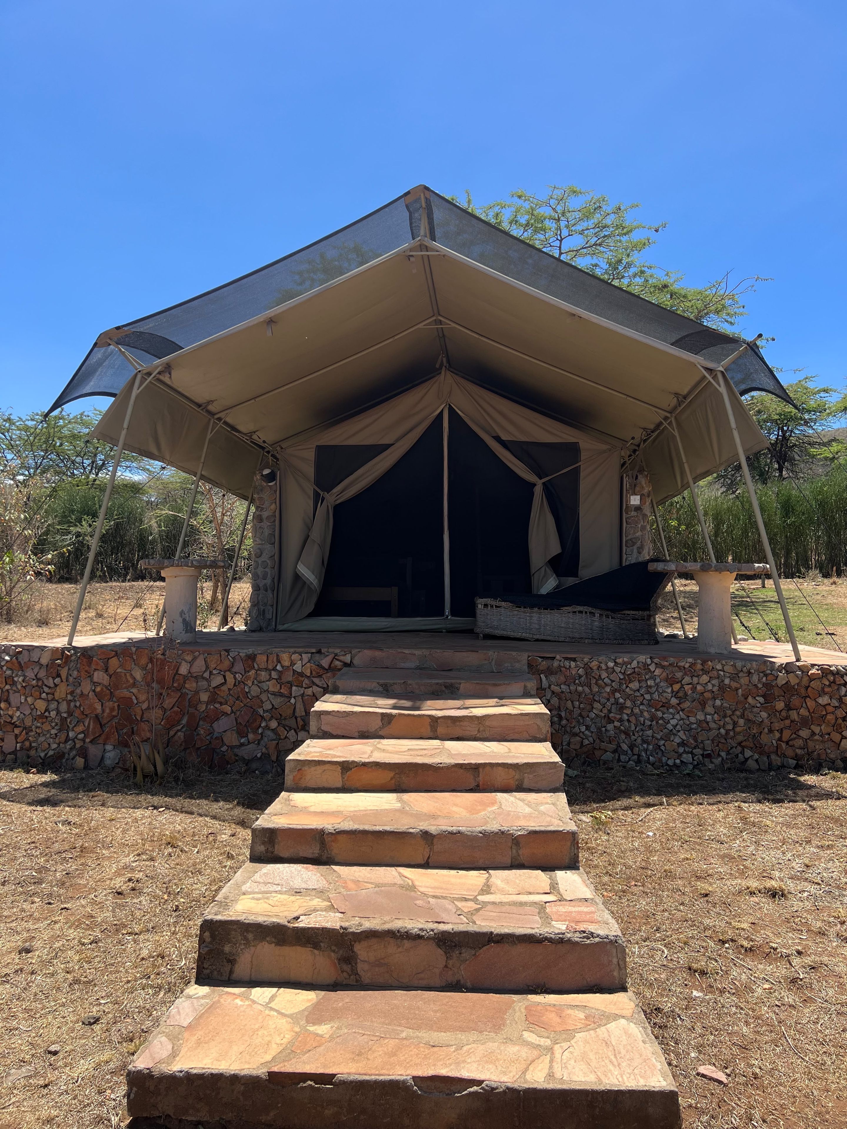 A tent with a stone wall and steps leading up to it.