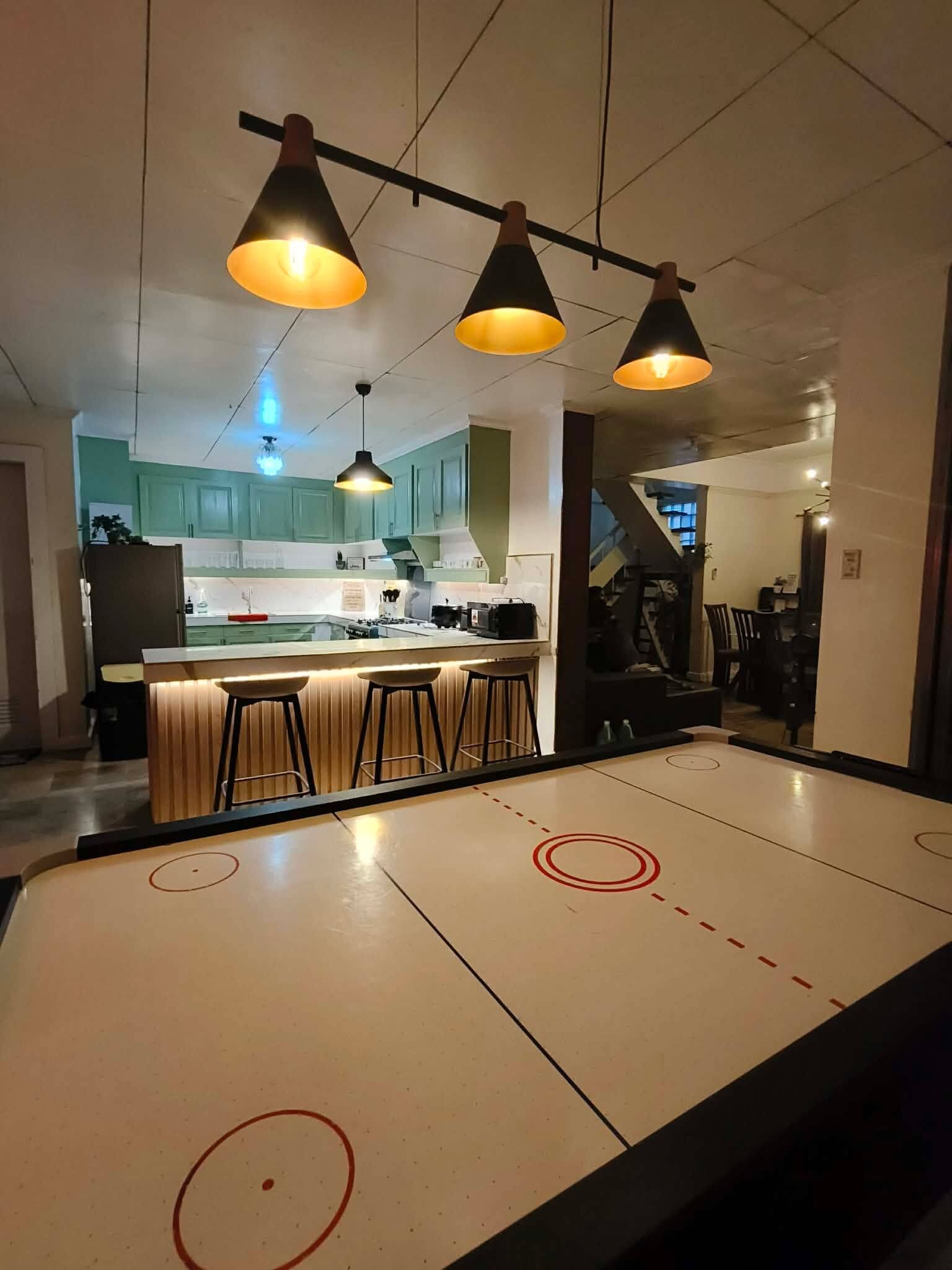 A modern kitchen with a bar area, pendant lighting, and a dining table with a unique design.