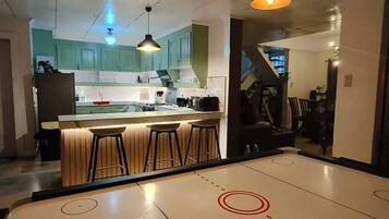 A modern kitchen with a bar area, pendant lighting, and a dining table with a unique design.