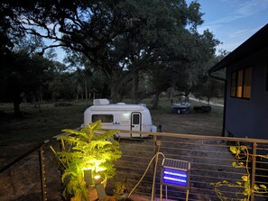 A campsite with a trailer, a boat, and a house in the background.