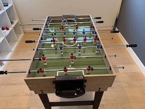 Een tafelvoetbaltafel met een houten frame, metalen stangen en twee teams spelers.