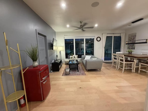 A modern living room with a sofa, coffee table, and a dining area with chairs.