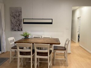 A dining area with a wooden table and six chairs, a potted plant, and a wall-mounted light fixture.