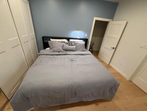 A bedroom with a bed, a nightstand, a lamp, and a wardrobe.