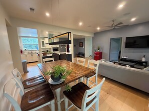 A modern kitchen with a dining area, a red refrigerator, and a flat-screen TV.