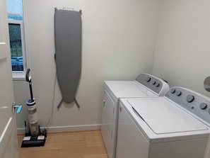Una sala amb rentadora, assecadora, planxa i aspiradora.