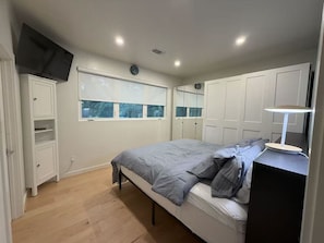 A bedroom with a bed, a bedside table, a wardrobe, and a window.