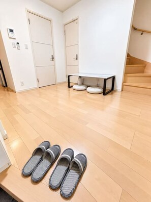A room with a wooden floor, a bench, and a pair of slippers. - Tokyo Koiwa | Private 2-Bedroom Stay for 5 Guests (江戸川区東小岩5-25-14)