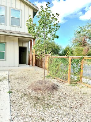 A residential property with a gravel driveway, a wooden fence, and a house with a number 855 on the door. - Newly Built 3-bedroom modern house with parking in vibrant Downtown San Antonio (San Antonio)