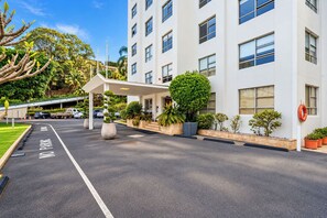 A modern hotel entrance with a covered walkway, a no parking sign, and a variety of potted plants. - 1BR Harbour View Nest Opal (McMahons Point)