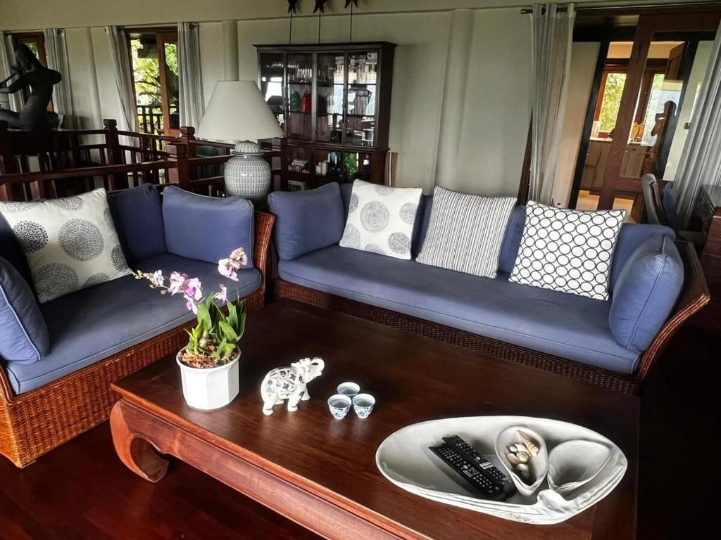 Una sala de estar con un sofá azul, una mesa de centro de madera y una lámpara decorativa.