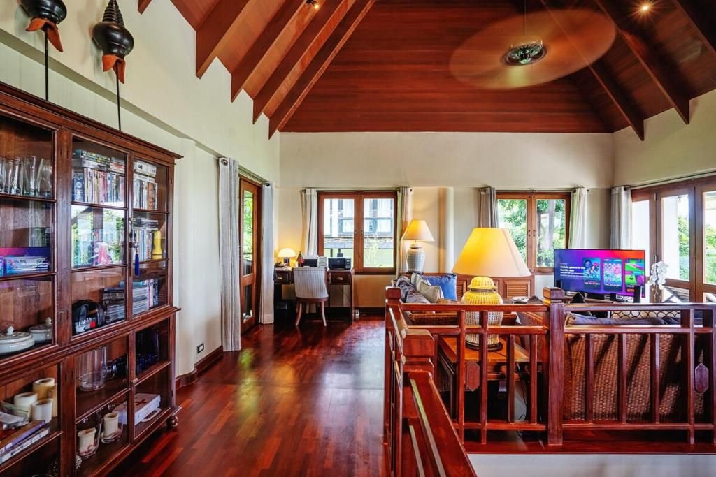 Una habitación amplia con techo de madera, televisión, estantería y zona de comedor con mesa y sillas.