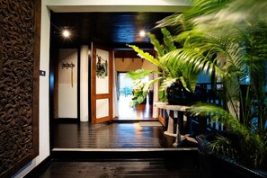 Un interior tradicional con suelo de madera, un panel decorativo en la pared y una planta en maceta.