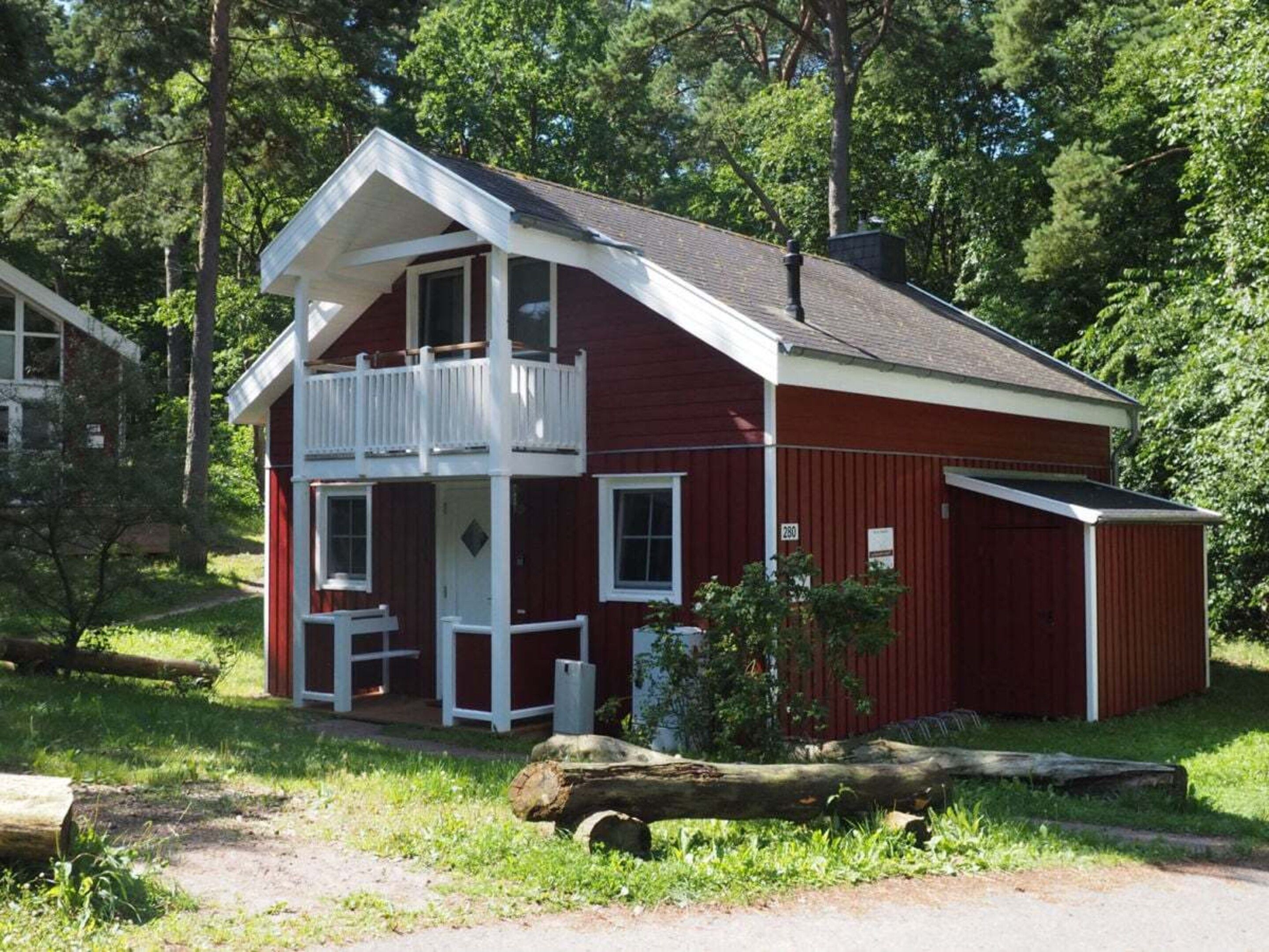 A two-story red house with a balcony, a porch, and a garage.