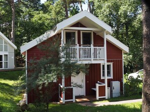 A two-story cabin with a balcony, surrounded by trees. - Holiday Home Seebar (Ostseebad Baabe)