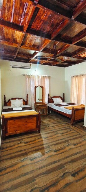 A room with two wooden beds, a wooden dresser, a mirror, and a ceiling with exposed beams. - Cozy Homestay Steps Away from Alappuzha Beach (Alappuzha)