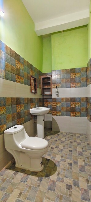 A bathroom with a toilet, sink, and tiled walls. - Cozy Homestay Steps Away from Alappuzha Beach (Alappuzha)