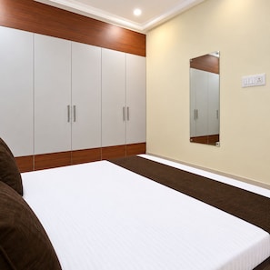 A bedroom with a bed, wardrobe, and a mirror on the wall.