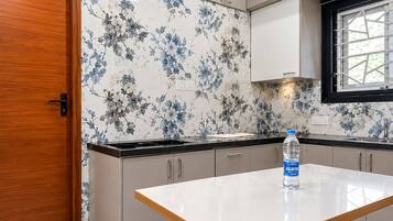 Una cocina moderna con puerta de madera, encimera blanca y una botella de agua sobre la encimera.