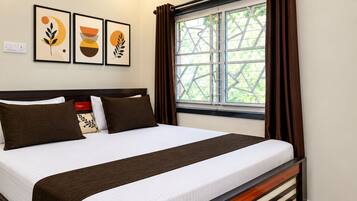 Habitación de hotel con cama, aire acondicionado, ventana con cortinas y decoración en la pared.