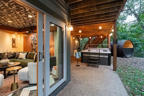 A modern outdoor living area with a hot tub, a staircase, and a covered seating area. - Luxe Cabin •Sauna•Hot Tub•Theater•Arcade•6 Kings (Galena)