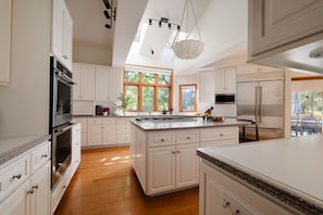 A spacious kitchen with white cabinetry, a large island, stainless steel appliances, and a skylight. - Luxe Cabin •Sauna•Hot Tub•Theater•Arcade•6 Kings (Galena)