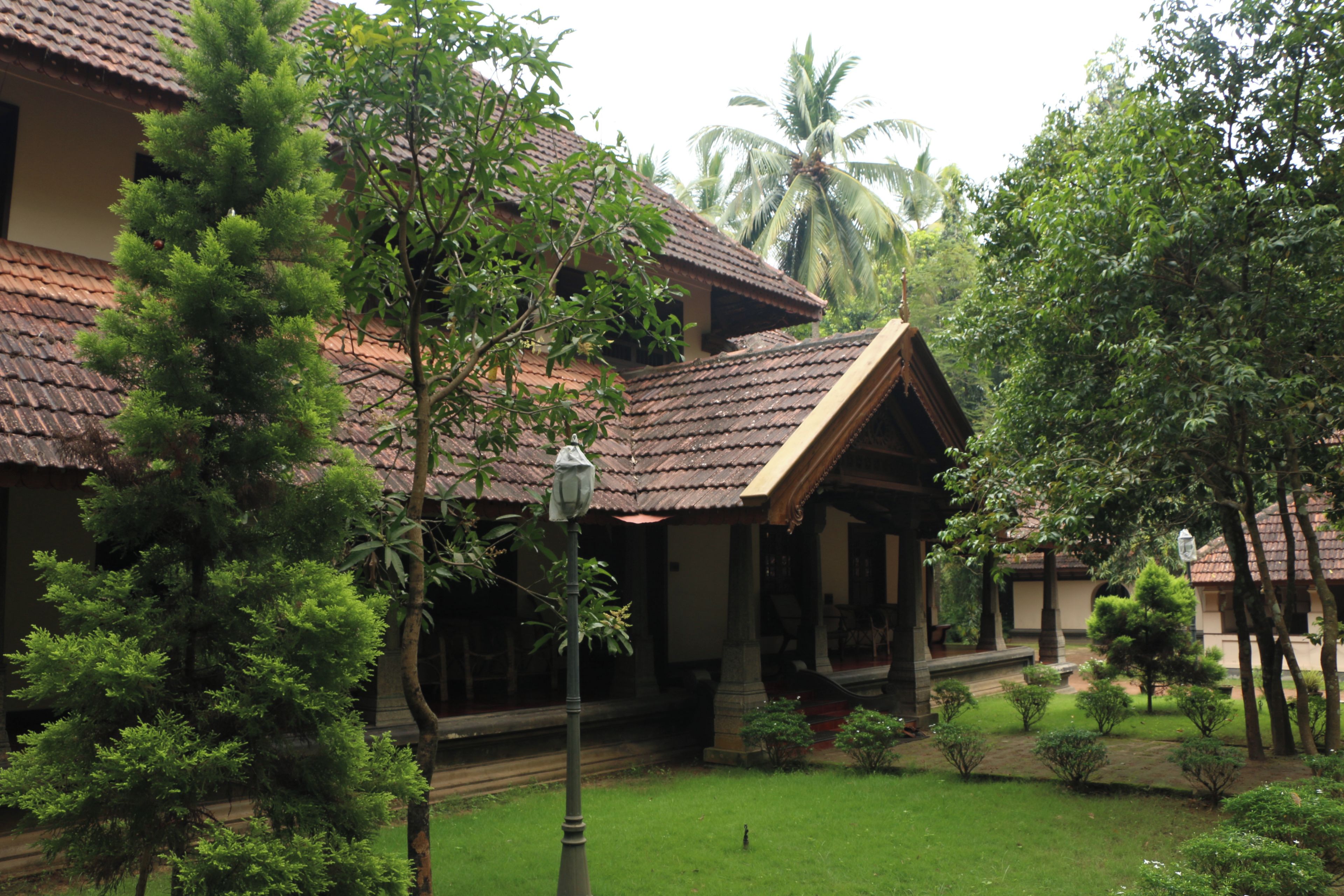 A traditional building with a tiled roof, surrounded by lush greenery and palm trees.