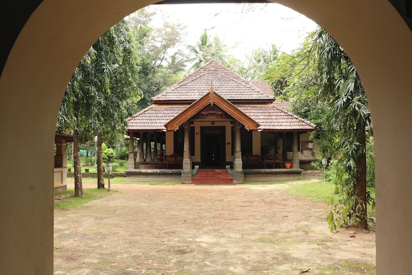 A traditional building with a tiled roof, a central entrance, and a surrounding garden.