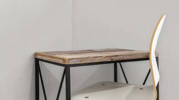 Una mesa en esquina con tapa de madera y estructura metálica negra, acompañada por una silla blanca con respaldo curvo.