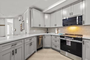 Una cocina moderna con armarios blancos, electrodomésticos de acero inoxidable y un salpicadero de azulejos.