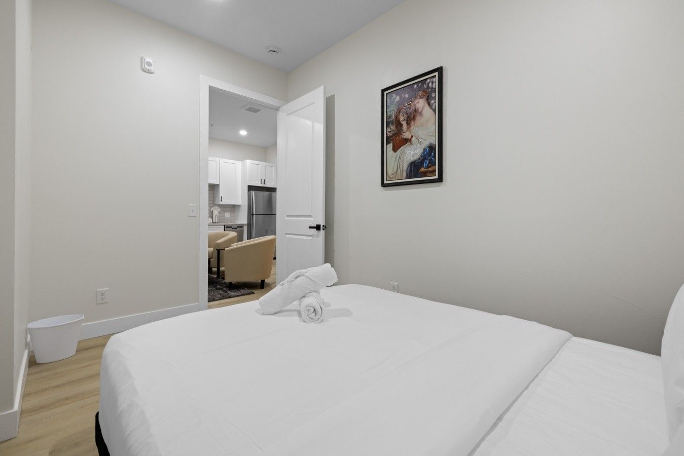 Een hotelkamer met een bed, een schilderij en uitzicht op de keuken.