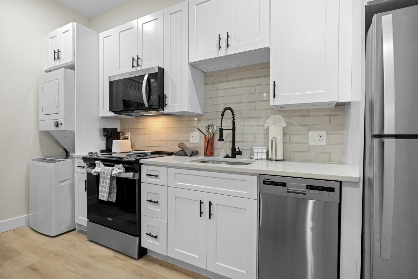 Una cocina moderna con armarios blancos, electrodomésticos de acero inoxidable y un salpicadero de azulejos.