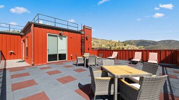 Una terraza en la azotea con mobiliario exterior y un edificio rojo.